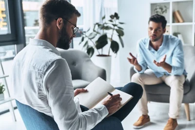two men sitting in chairs and having a discussion