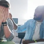 man in group therapy covering his face