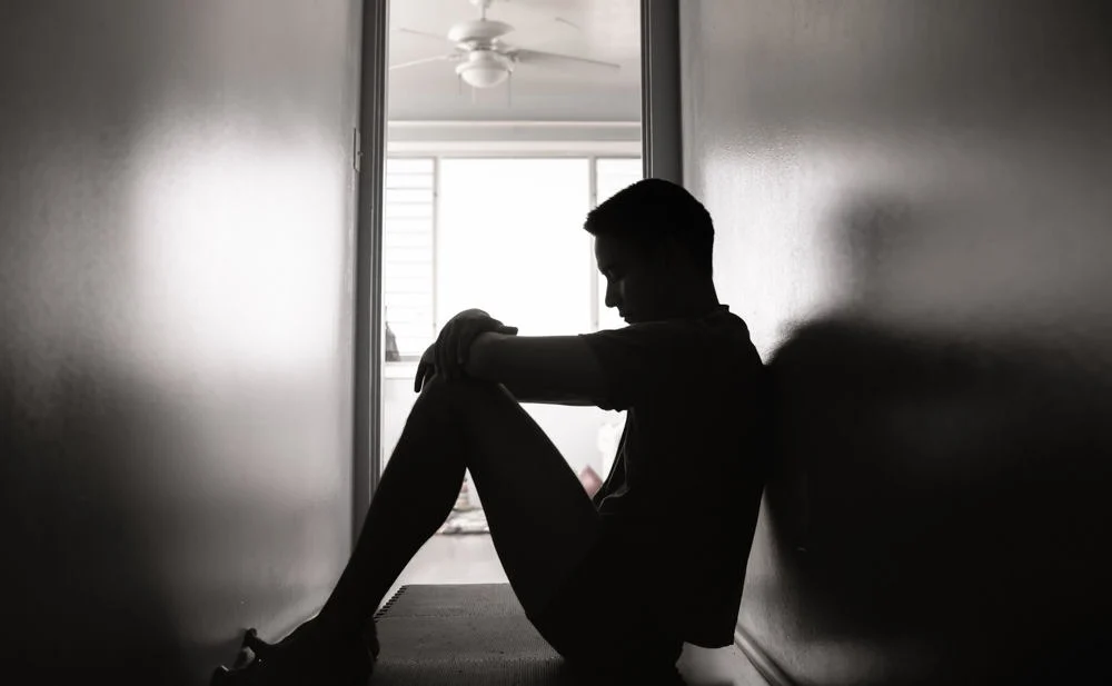 man sitting alone on the floor in a hallway