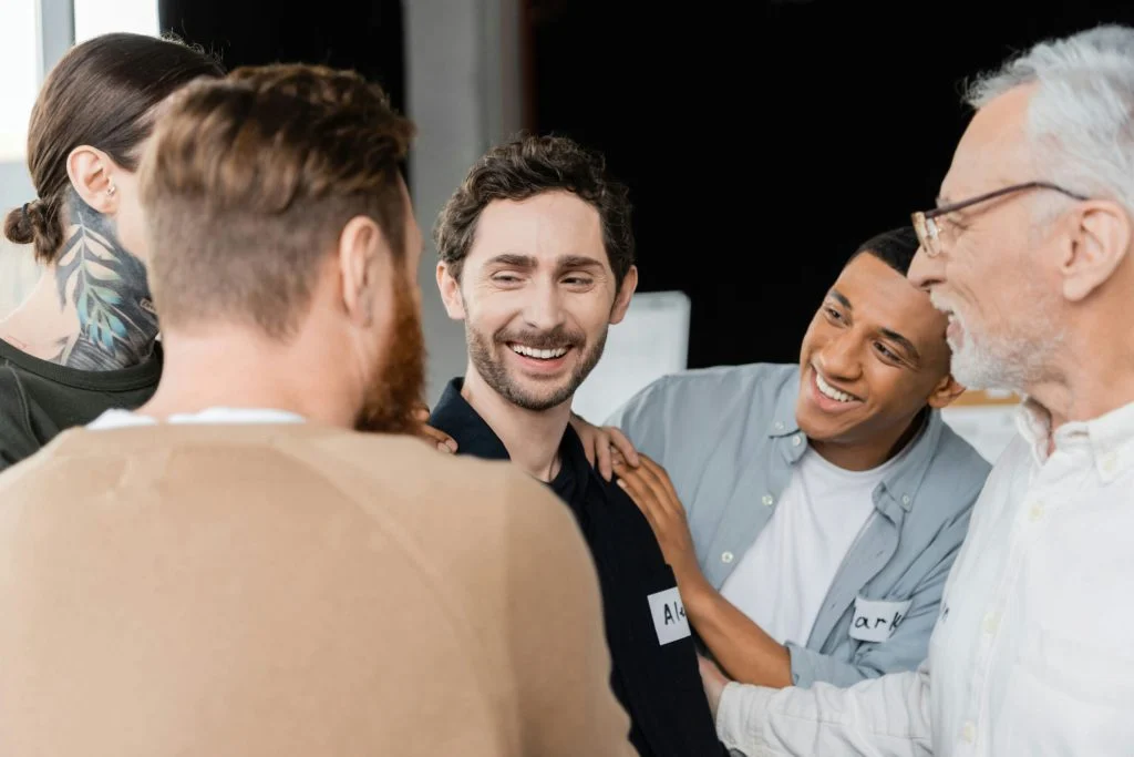 Men in a support group sharing encouragement, symbolizing male-specific healing and recovery in addiction treatment.