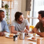 three sober curious men at breakfast together laughing