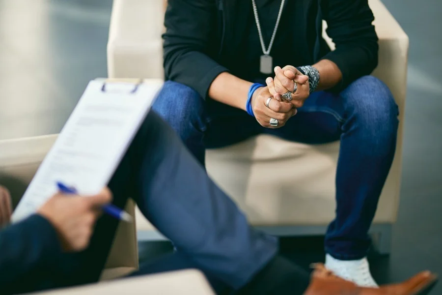 man thinking while sitting on a couch across from his therapist