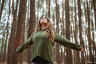 woman with arms spread wide smiling and enjoying nature
