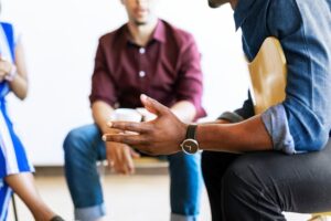 man sitting backwards in a chair discussing his addiction recovery