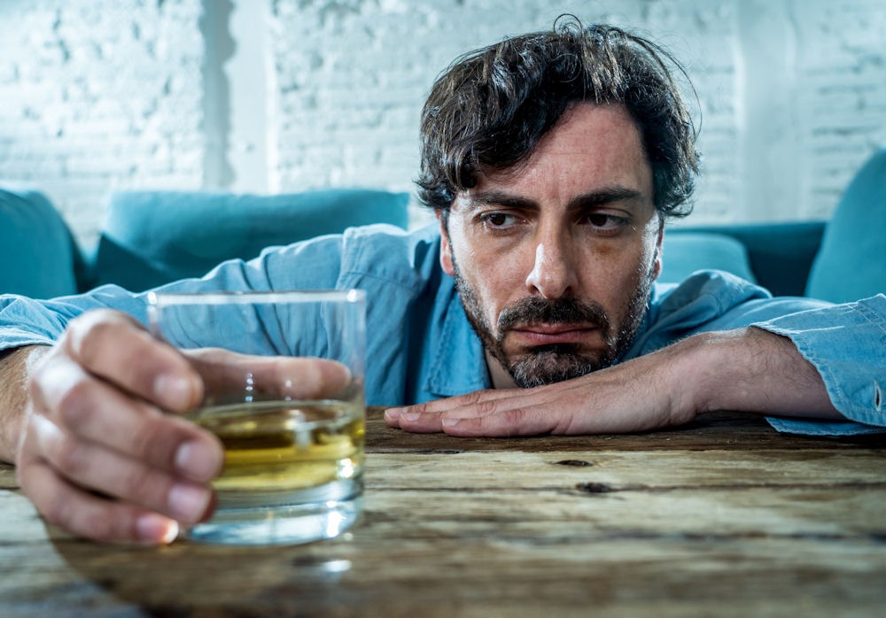 man resisting relapse while looking at a drink
