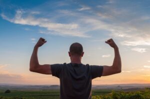 man flexing both biceps while looking over Colorado landscape