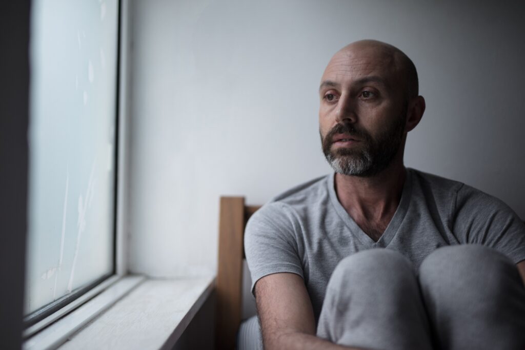 sad man sitting by a window with insomnia