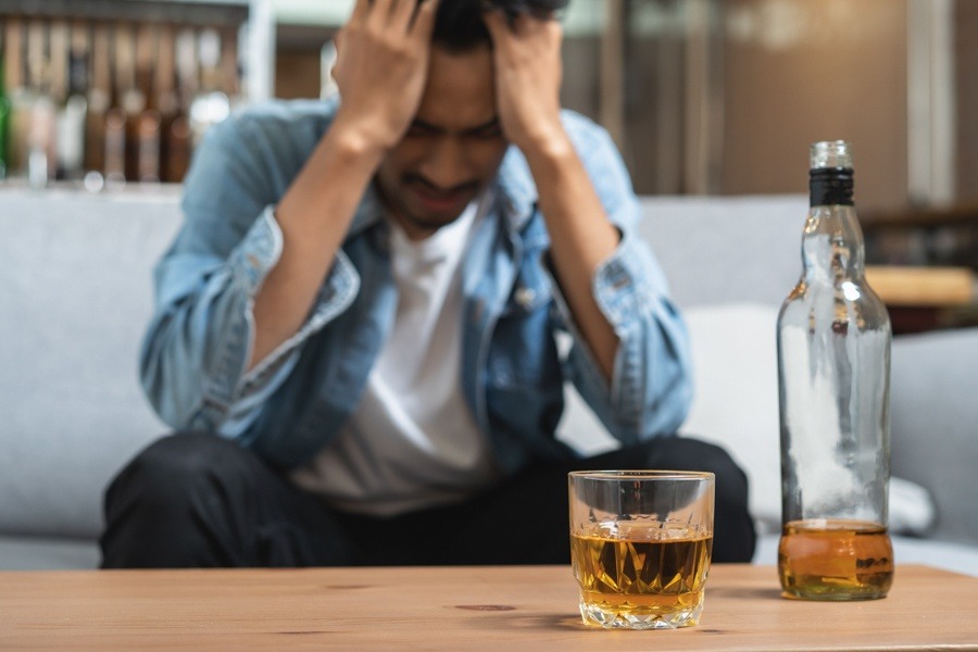 Person holding their head and appearing dizzy or unwell, depicting a negative reaction to mixing Wellbutrin and alcohol.