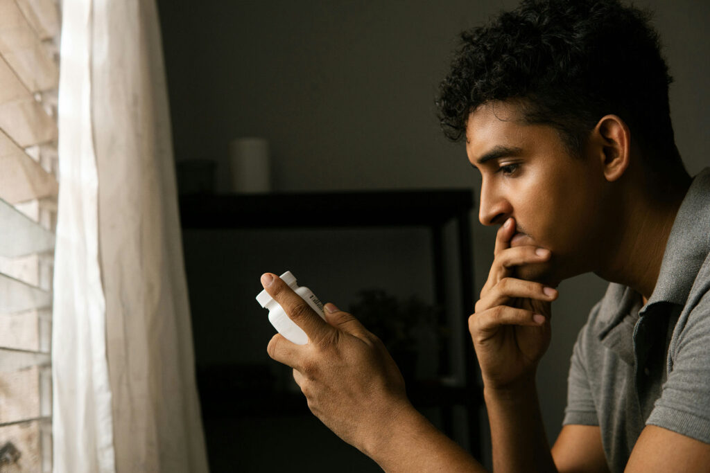man looking at a prescription bottle of Wellbutrin, wondering about the potential risk of mixing it with alcohol.